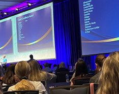 A speaker stands podium in front of large audience at CFMA 2023