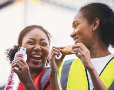 Two women in vests laughing/Adobe Stock 